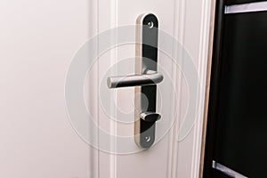 White door and handle. Modern chrome handle in your hotel room or home. Entrance to an apartment, office, or bedroom.