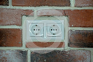 White double socket is built into the brick wall