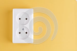 White double socket isolated on yellow background. Electric lighting