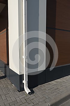 White drainpipe at the corner of the building.