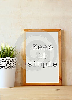 White drawing board with the phrase keep it simple written on it against textured wall