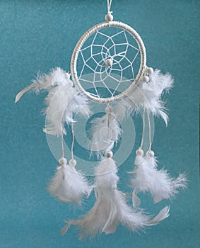 White Dreamcatcher with feathers on the blue baackground. Ethnic amulet of  native american, indian interior decoration