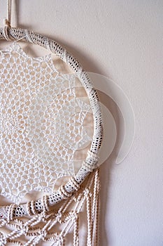 White dreamcatcher hanging on a white wall. Boho interior decor
