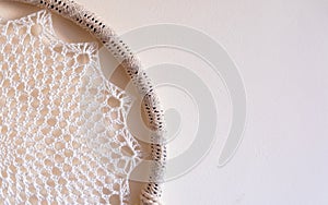 White dreamcatcher hanging on a white wall. Boho interior decor