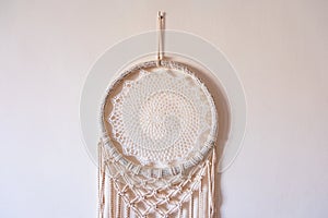 White dreamcatcher hanging on a white wall. Boho interior decor