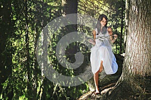 White dressed girl in evergreen summer forest