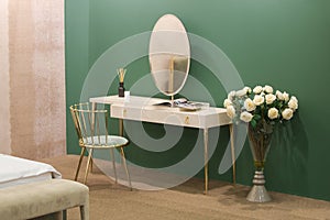 White dressing table with wicker elements, a room with a green wall and golden brass furniture, luxury mirror, female boudoir