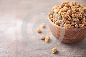 White dried mulberry in wooden bowl on wood textured background. Copy space. Superfood, vegan, vegetarian food concept. Macro of