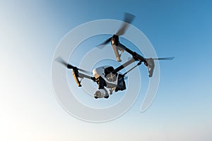 White drone with digital camera flying on sky background