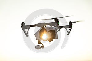 White drone with digital camera flying on sky background