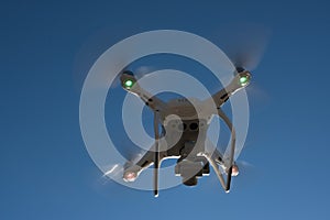 White drone hovering in a bright blue
