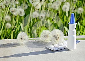 White dropper bottle mock up, blister with medical pills , dandelions on gray background with shadows. Concept of allergy photo