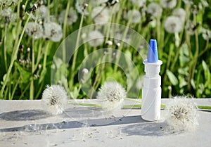 White dropper bottle mock up and dandelions on gray background with shadows with copy space. Concept of allergy treatment. Nose