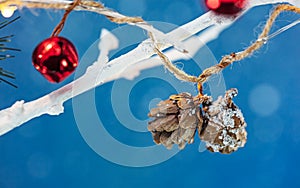 White dry tree branches decorated by christmas garland lights with pine cones and red jingle bell. macro view