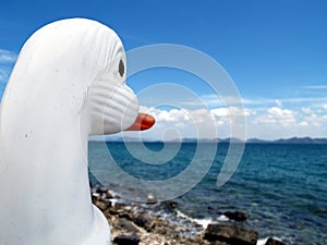 White duck boat on rocky beach looking to the sea and blue sky over horizon