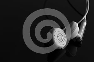 White earphones on reflective black photo