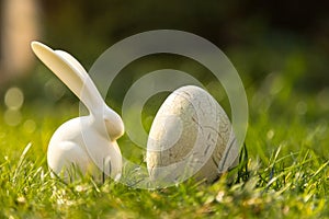 White Easter bunny figures and dyed eggs on the green grass in the field on a sunny day