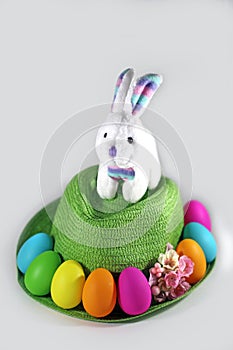 White Easter bunny rabbit on a Green straw hat with easter colorful eggs