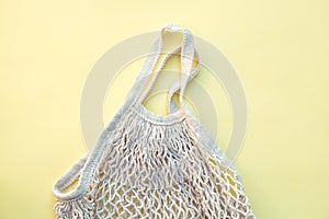 White eco-friendly string bag isolated on yellow background, responsible consumption