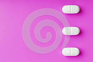 White Ecstasy pills in a row on a pink background, isolate.