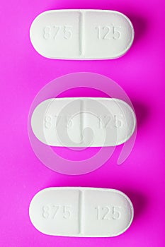 White Ecstasy pills in a row on a pink background, isolate
