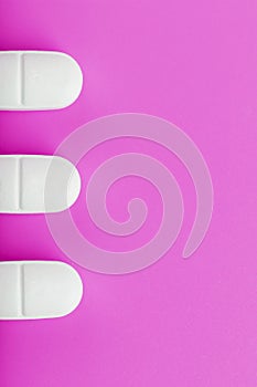 White Ecstasy pills in a row on a pink background, isolate.