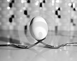 White egg balanced on two forks on the kitchen counter top.