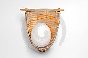 White egg in bamboo weave basket on white