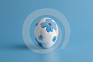 White egg  decorated with flowers on a blue background