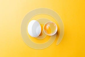 White egg and egg yolk on the yellow background. topview