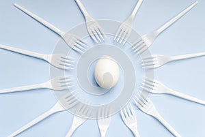 White egg and forks on a blue background