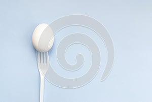 White egg and forks on a blue background