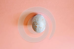 White egg with gold splashes on a soft pink background. Easter concept.