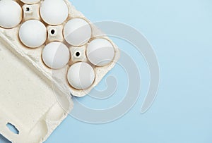 White eggs in cardboard on light blue background