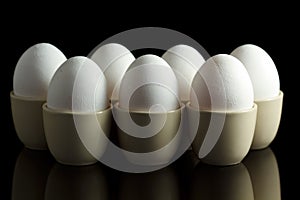 White eggs in egg-cups on black