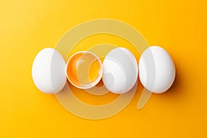 White eggs and egg yolk on the yellow background. topview