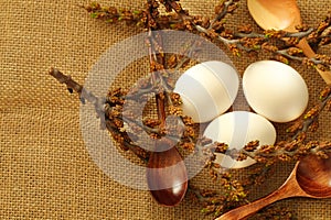 White eggs in a nest made of twigs with buds and wooden spoons for Easter in a rustic style