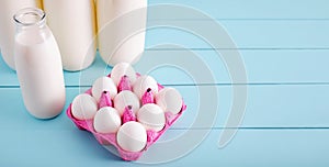 White eggs in a pink filler and milk bottles on turquoise wooden country kitchen table