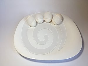 White eggs on a white plate on a white background. The birth of life. 4 Chicken eggs