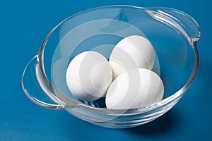 White eggs in plate on blue background