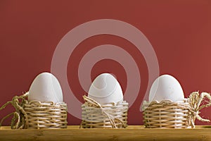 White eggs in small baskets and red background