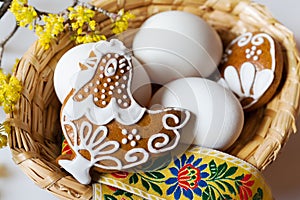 white eggs in wicker nest with decorated gingerbread hen cake with dogwood flower
