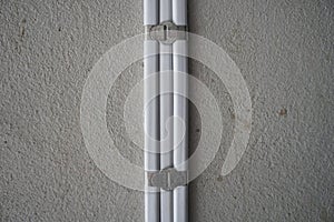 White electric cable attach on wall with aluminum cable clip. PVC insulated electrical wiring. With strap belt