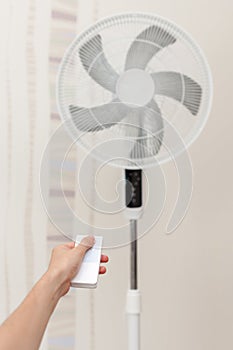 White electric fan turns on, turns off with the remote control. Hand hold electric fan remote