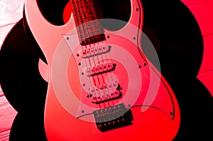 White electric guitar on wooden background. Old phonograph records. Retro music concept. Red shadows