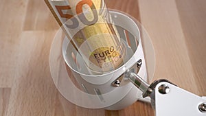 White electric lamp and Euro banknote close-up on a wooden surface