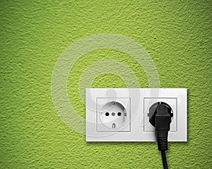 White electric outlet mounted on green wall