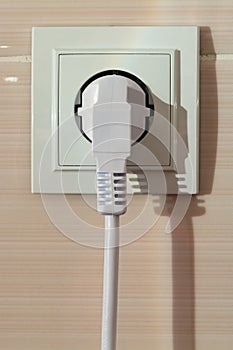 White electric power sockets on wall background with plugged electric plug