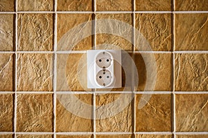 White electric socket on kitchen wall with ceramic tiles