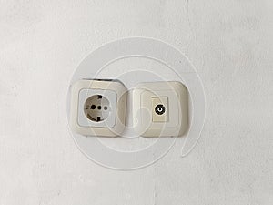 White electric socket on a white wall. Cable plug hole for electricity on the wall. Power Outlet for electric tools